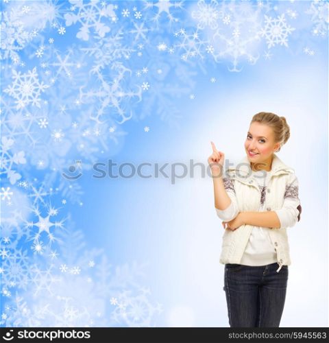 Young girl with fur hat showing pointing gesture on winter background
