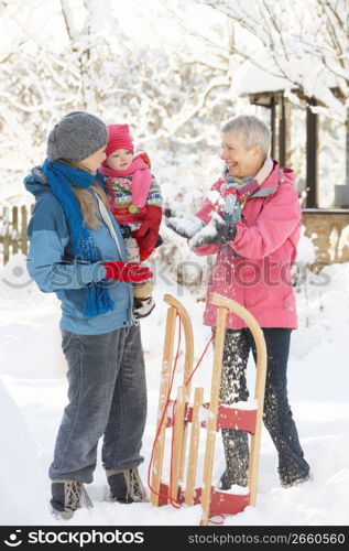 Young Girl With Grandmother And Mother Holding Sledge In Garden