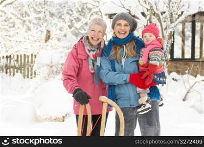 Young Girl With Grandmother And Mother Holding Sledge In Garden