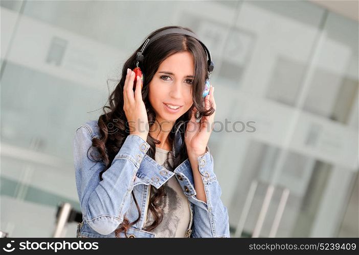 Young girl with headphones listening to the music and dancing in the street