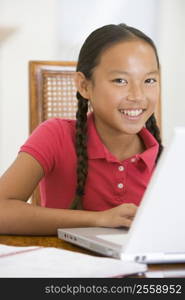 Young girl with laptop in dining room smiling