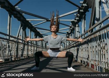 Young girl with long hair in hareografichnoy pose on the bridge