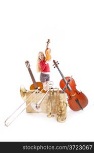 young girl with many musical instruments in box against white background
