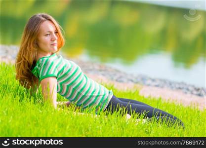 young girl with red hair resting near the pond