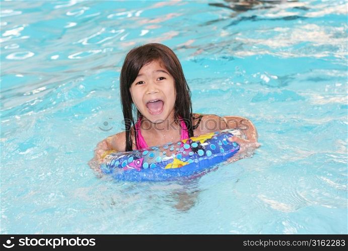 Young girl with rubber ring in swimming pool