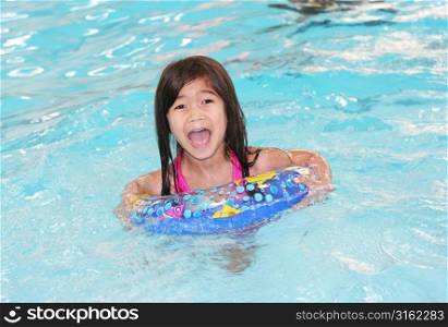 Young girl with rubber ring in swimming pool