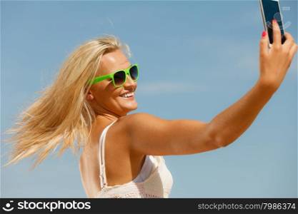 Young girl with sunglasses using her mobile phone to taking selfie. Active relax in summer. Social network and internet concept.