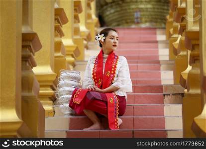 Young girl with traditional Burmese holding bowl of rice on the hand at beautiful golden pagoda in Myanmar