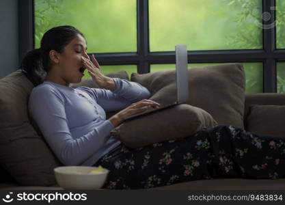 YOUNG GIRL YAWNING WHILE ATTENDING ONLINE CLASS