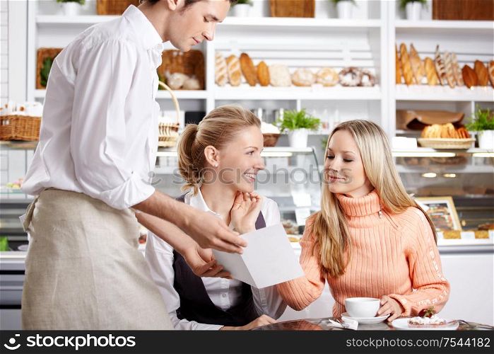 Young girls do the order to the waiter in cafe