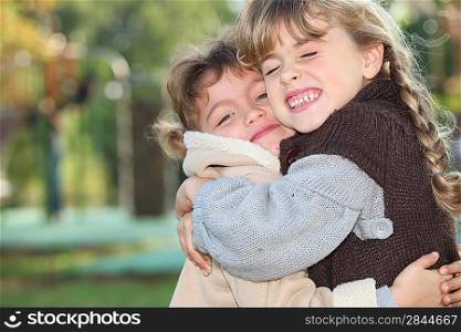 Young girls hugging outside