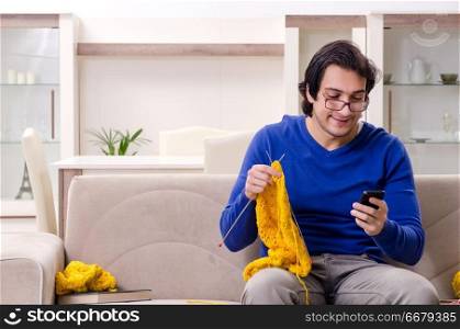 Young good looking man knitting at home