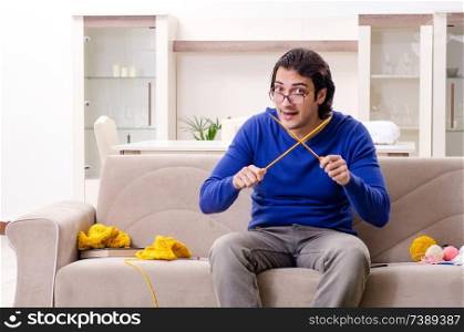 Young good looking man knitting at home