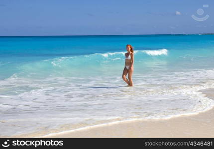 Young graceful woman goes on coast of ocean