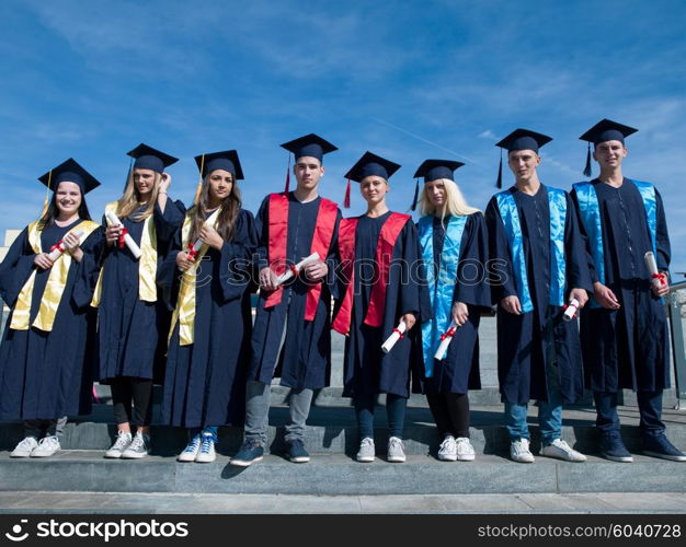 young graduates students group standing in front of university building on graduation day