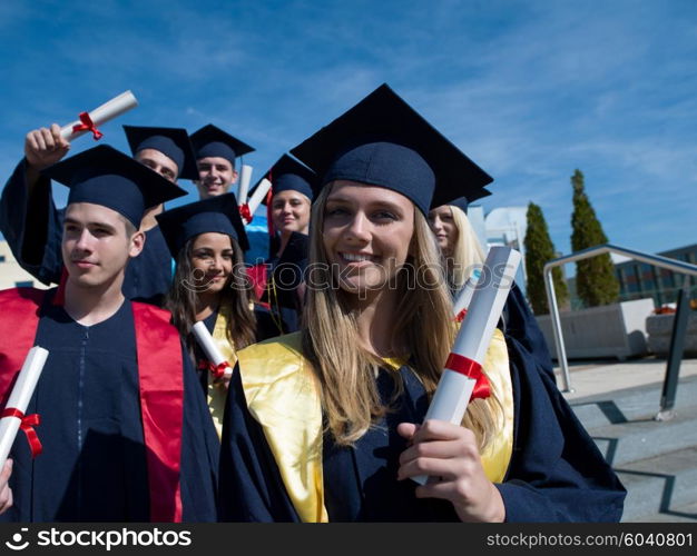 young graduates students group standing in front of university building on graduation day