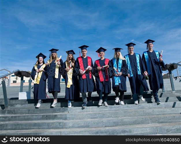 young graduates students group standing in front of university building on graduation day