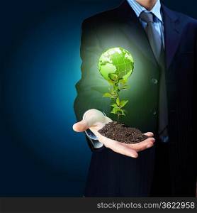 Young green plant in the hand of a businessman