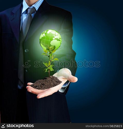 Young green plant in the hand of a businessman Elements of this image furnished by NASA.