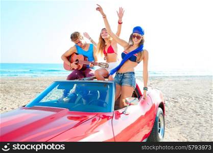 young group having fun on the beach playing guitar and dancing in a convertible car