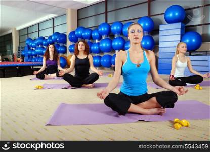 young group of girls exercising yoga in lotus flower position
