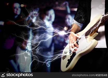 Young guitar player with instrument performing in night club