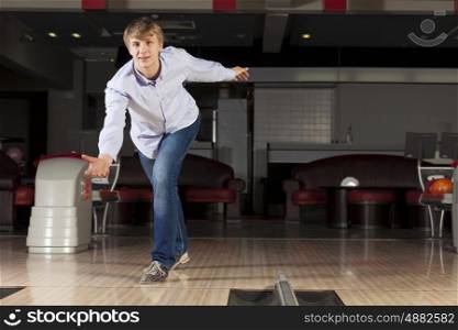 Young guy at bowling club throwing ball. Guy playing bowling