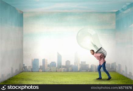Young guy carrying light bulb on his back. Carrying out an idea