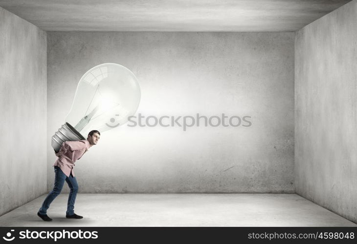 Young guy carrying light bulb on his back. Carrying out an idea