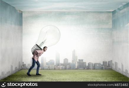 Young guy carrying light bulb on his back. Carrying out an idea