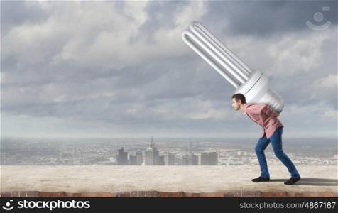 Young guy carrying light bulb on his back. Guy carrying light bulb
