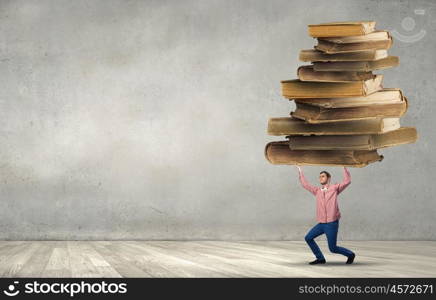 Young guy carrying pile of old books. I have to study hard