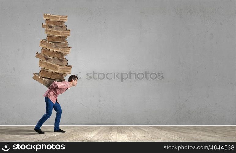 Young guy carrying pile of old books. I have to study hard