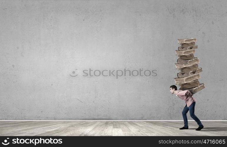 Young guy carrying pile of old books. I have to study hard