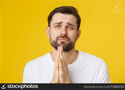 Young guy dressed casually isolated on yellow background, having put hands together in prayer or meditation, looking relaxed and calm. Young guy dressed casually isolated on yellow background, having put hands together in prayer or meditation, looking relaxed and calm.