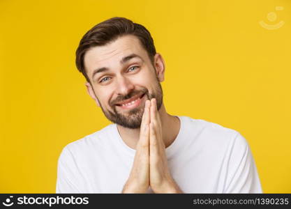 Young guy dressed casually isolated on yellow background, having put hands together in prayer or meditation, looking relaxed and calm. Young guy dressed casually isolated on yellow background, having put hands together in prayer or meditation, looking relaxed and calm.