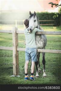 Young guy hugs his friend?s horse