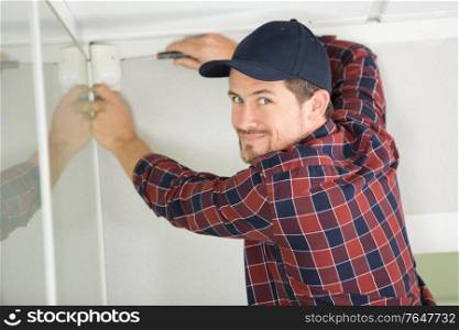 young guy repairs video surveillance on a light ceiling