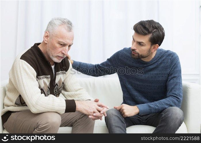 young guy with hand shoulder aged sad man settee