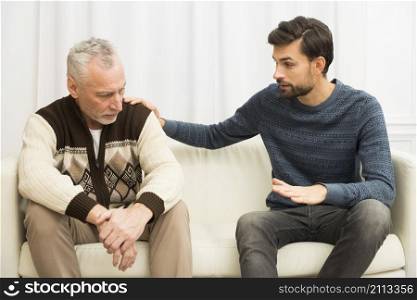 young guy with hand shoulder aged sad man sofa