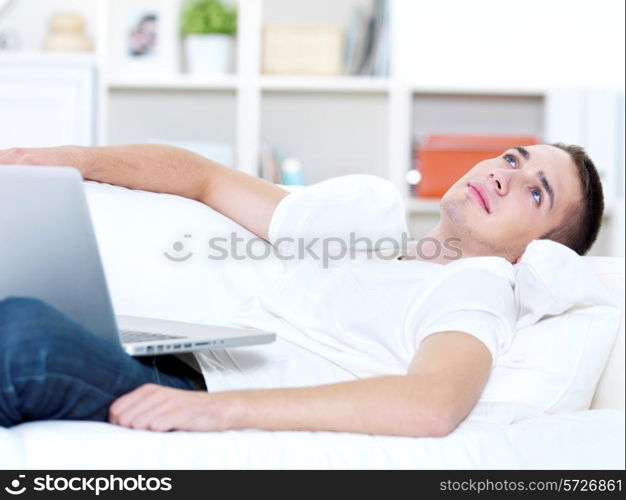 young guy with laptop look outside on the sofa