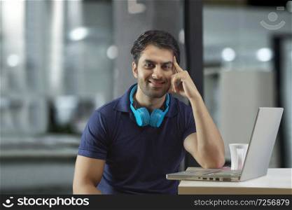 Young guy working in office using headset and laptop hand rests on the cheek