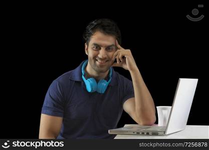 Young guy working using headset and laptop over black background hand rests on the cheek