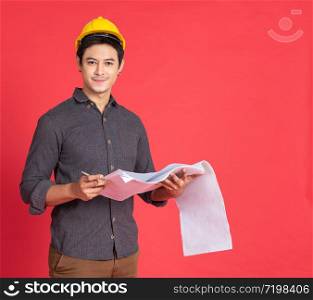 Young handsome asian man in casual dress with yellow hardhat hand holding paperwork blueprint in architect and engineer worker isolated in red background in studio.
