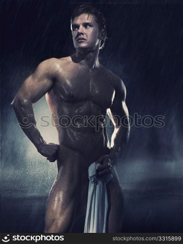 Young handsome athlete standing in the rain