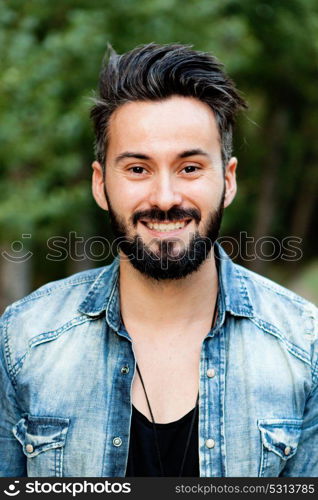 Young handsome bearded hipster man with denim shirt in the park