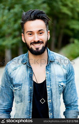 Young handsome bearded hipster man with denim shirt in the park