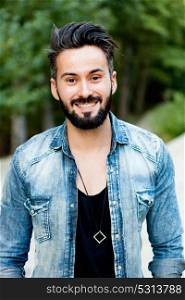 Young handsome bearded hipster man with denim shirt in the park