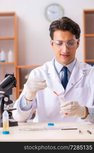 Young handsome biochemist working in the lab  