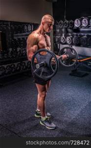 Young handsome bodybuilder lifting heavy barbell in a gym. Bodybuilder with barbell